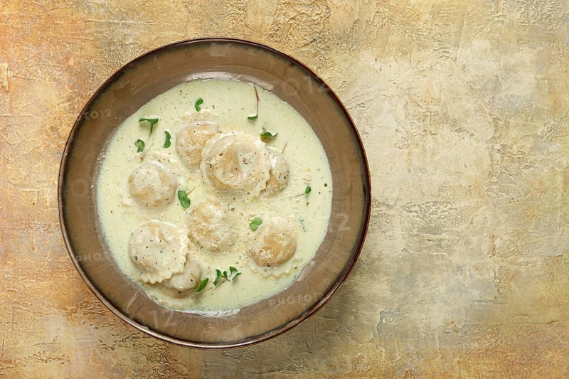 Ravioli in cream sauce, spices and herbs, top view, no people
