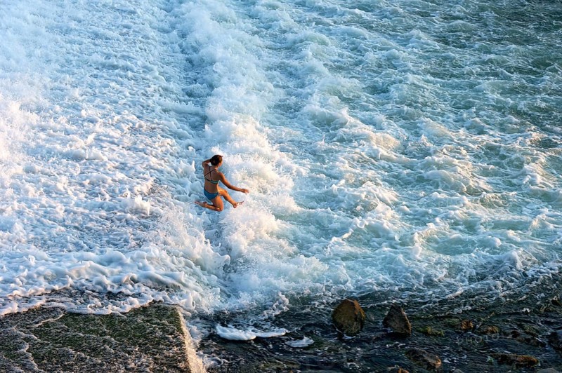 Girl bathing in the spray of the Lech weir, jumping into the white foaming water of the cascades, river Lech, Landsberg am Lech, Upper Bavaria, Bavaria, Germany, Europe