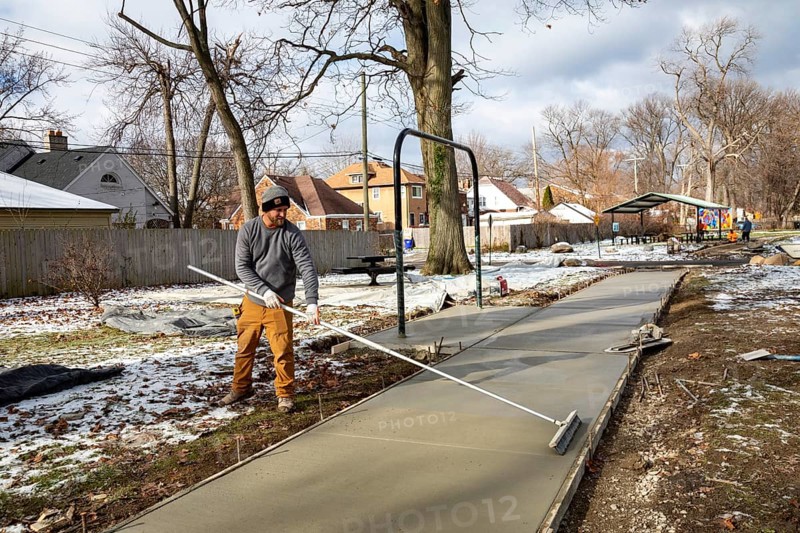 Detroit, Michigan - Workers pour and finish concrete for walking paths in Three Mile Park in Detroit's Morningside neighborhood.