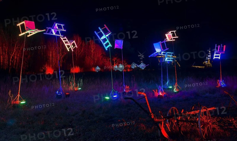 Colourful chairs on poles in the night landscape with wagon wheels in the foreground, world of lights, illumination, Mill Museum, Gifhorn, Lower Saxony, Germany, Europe