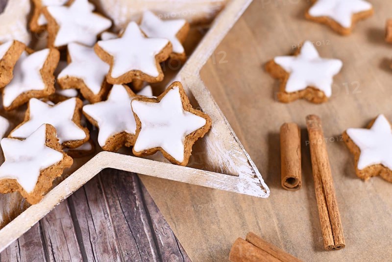 German star shaped glazed Christmas cinnamon cookies called 'Zimtsterne' made with almonds, egg white, sugar, cinnamon and flour in star shaped wooden bowl