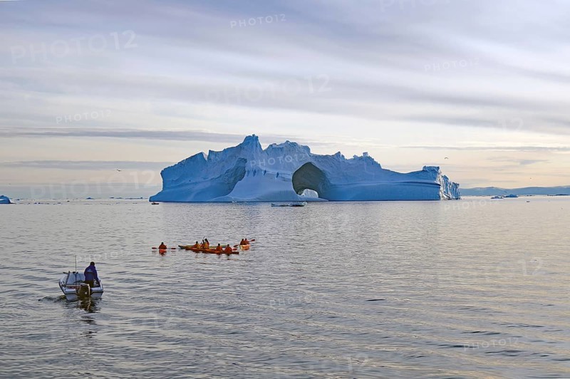 Small boat and kayaker in front of iceberg with large ice cave, Ilulissat, Disko Bay, Denmark, Greenland, North America
