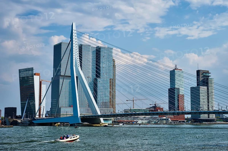 ROTTERDAM, THE NETHERLANDS, MAY 11, 2017: View of Rotterdam sityscape with Erasmusbrug bridge over Nieuwe Maas and modern architecture skyscrapers with speed boat passing uner the bridge