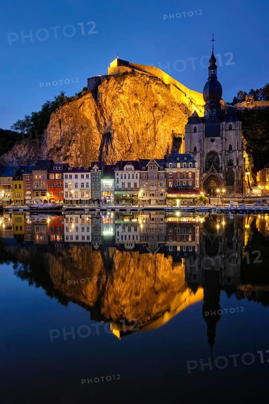 Night view of Dinant town, Collegiate Church of Notre Dame de Dinant over River Meuse and Pont Charles de Gaulle bridge and Dinant Citadel illuminated in the evening. Dinant, Belgium, Europe