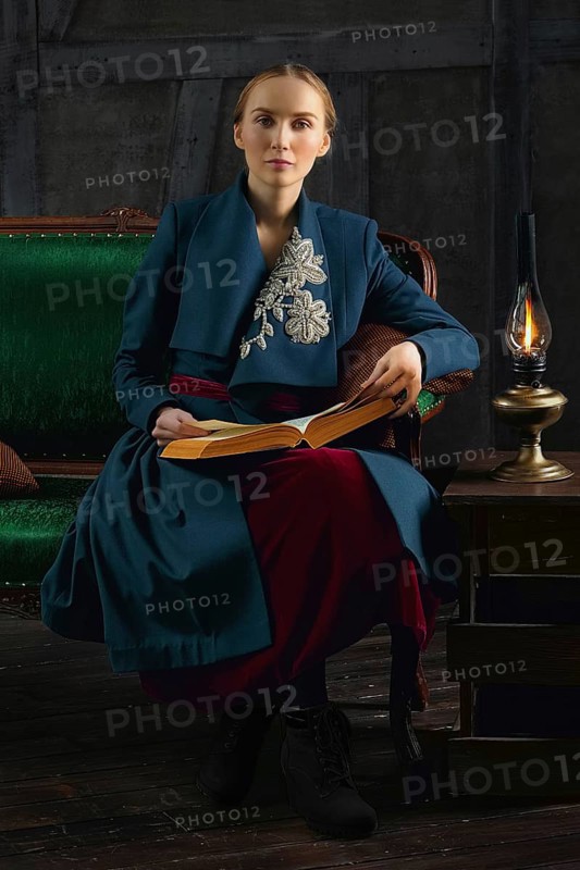 Attractive lady in oldfashioned clothes reading ancient book near vintage kerosene lamp
