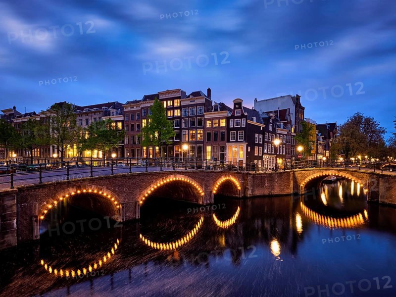 Night view of Amterdam cityscape with canal, bridge and medieval houses in the evening twilight illuminated. Amsterdam, Netherlands