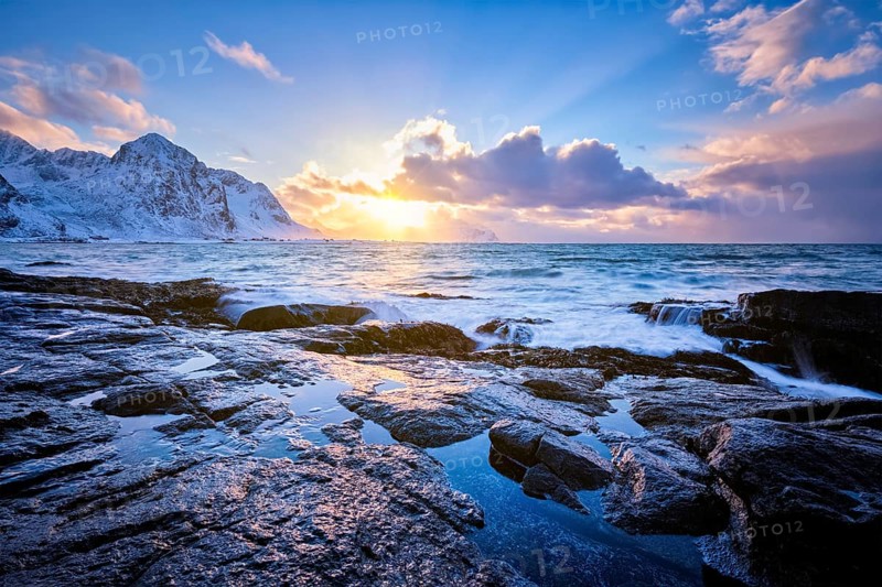 Beach of Norwegian sea on rocky coast in fjord on sunset in winter. Vareid beach, Lofoten islands, Norway, Europe