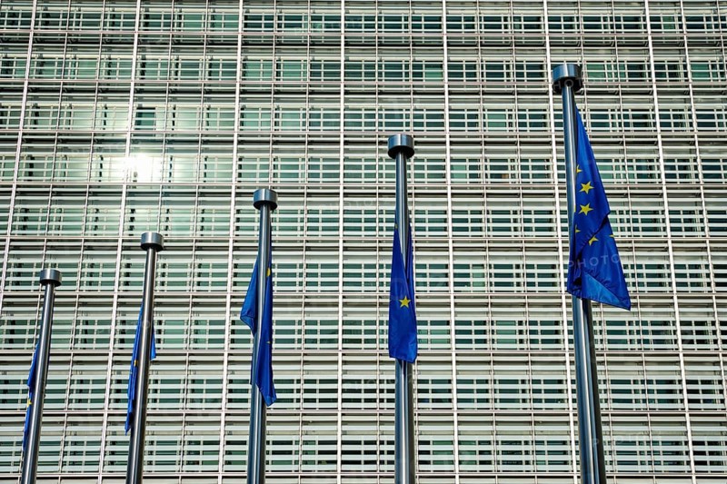 Helplessly drooping EU European Union flags with the European Comission building in Background. Brussles, Belgium, Europe