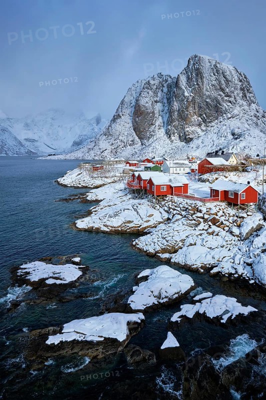 Iconic Hamnoy fishing village on Lofoten Islands, Norway with red rorbu houses. With falling snow in winter