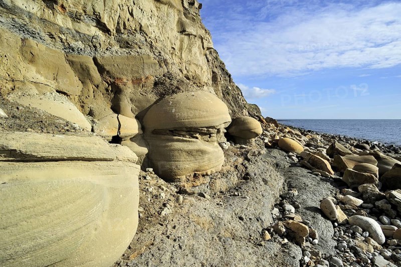 Rounded nodules on the beach near Osmington Mills, made of calcite-cemented sandstone, come from the Bencliff Grit Formation along the Jurassic Coast, Dorset, southern England, UK