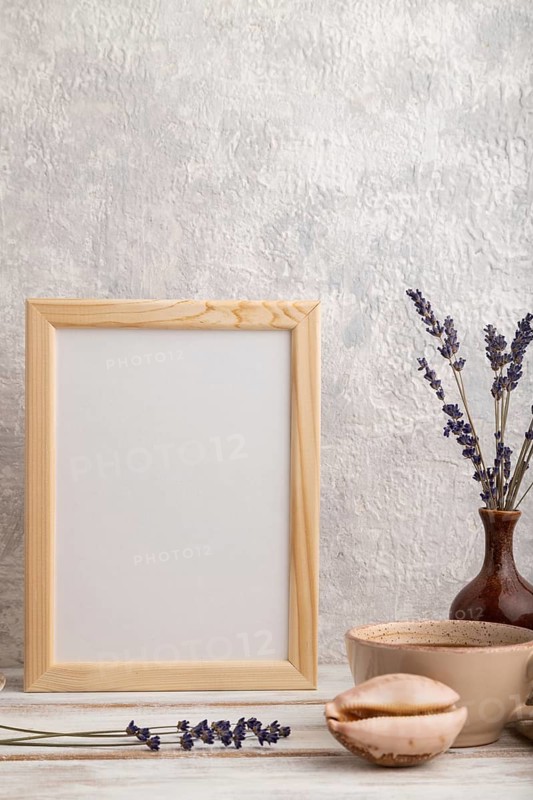 White wooden frame mockup with lavender in ceramic vase, linen textile, cup of coffee and bun on gray concrete background. Blank, vertical orientation, still life