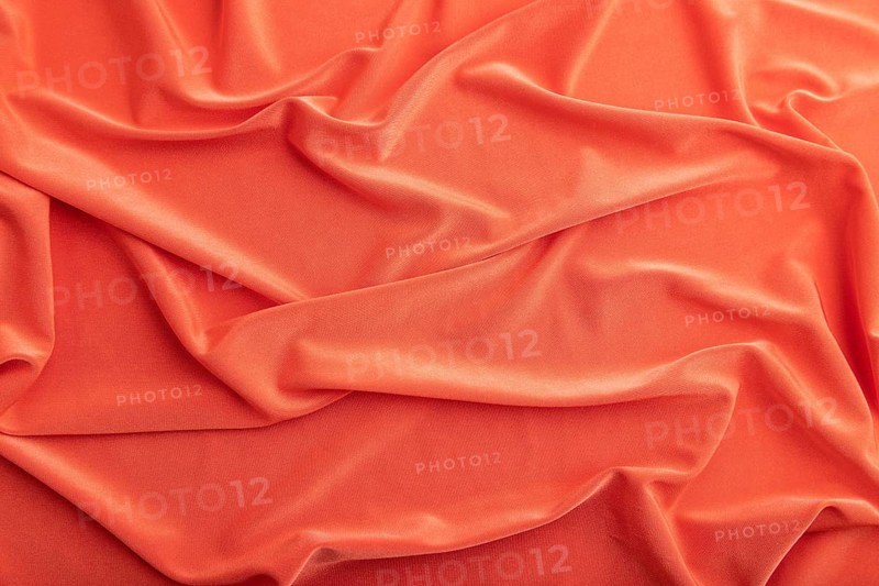 Fragment of red silk tissue. Top view, natural textile background and texture. wave concept, abstract