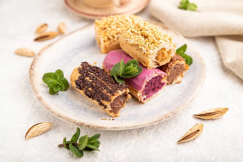 Set of eclair, traditional french dessert and cup of coffee on gray concrete background and linen textile. side view, close up, selective focus, still life. Breakfast, morning, concept