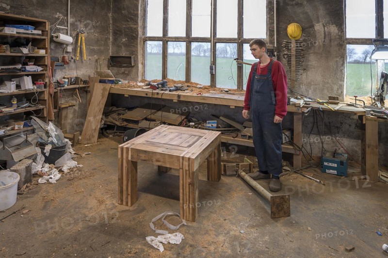 Young man standing in front of his finished table in the Wertkstatt, Mecklenburg-Vorpommern, Germany, Europe