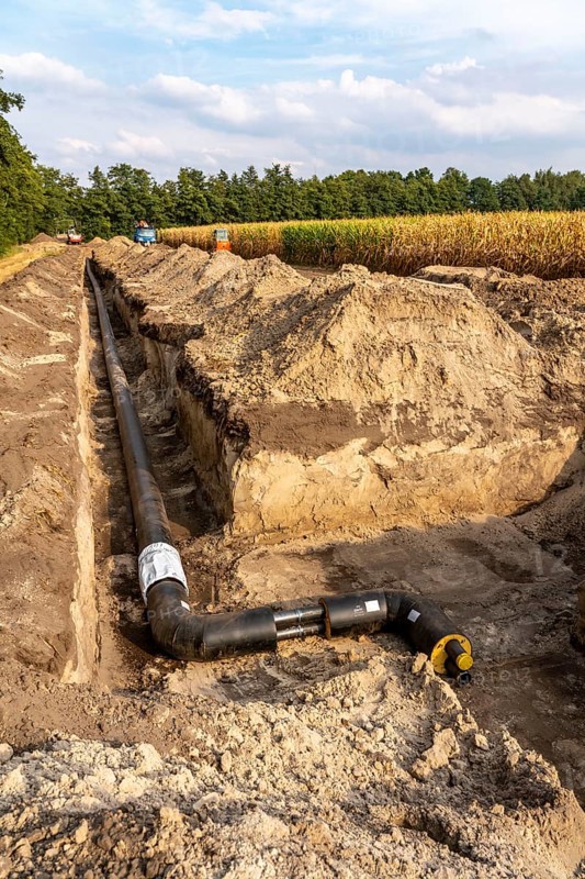 Laying of district heating pipes, next to a field, with maize, the district heating comes from a biogas plant and is fed directly into households in the neighbourhood, private provider, near Delbrück, North Rhine-Westphalia, Germany, Europe