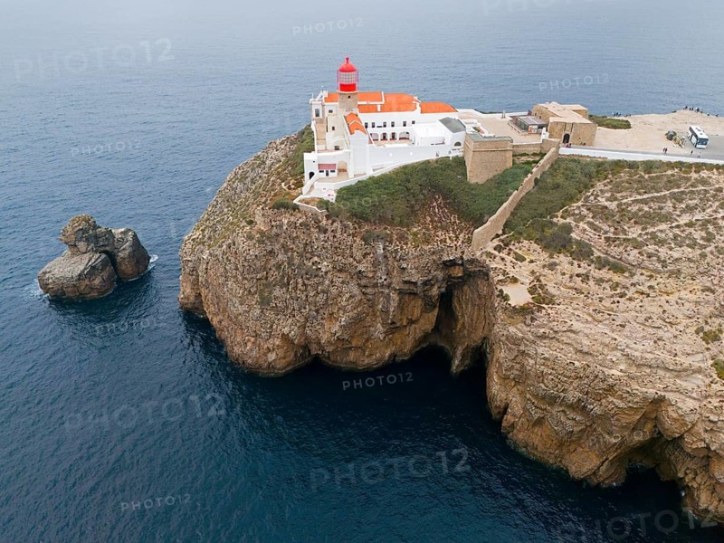 A red lighthouse and white buildings on a rocky cliff overlooking the ocean, an isolated feeling, aerial view, lighthouse, Cabo de São Vicente, Cape St Vincent, Cape St Vincent, Sagres, Portugal, Europe