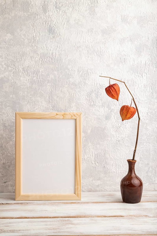 White wooden frame mockup with physalis in ceramic vase on gray concrete background. Blank, vertical orientation, still life, copy space