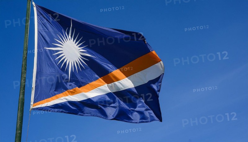 The flag of the Marshall Islands, Pacific Islands, flutters in the wind, isolated against a blue sky