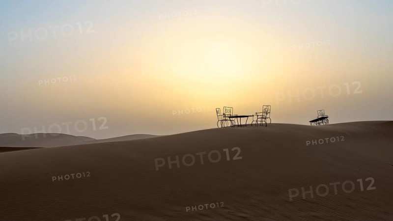 Sunset, cast iron table and chairs in the sand dunes of Erg Chebbi, Sahara, Merzouga, Morocco, Africa