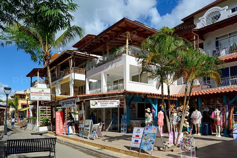 A lively street scene in a tropical town with wooden architecture and various shops, Bayahibe, Dominican Republic, Hispaniola, Caribbean, America, Central America
