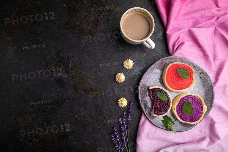 Sweet tartlets with jelly and milk cream with cup of coffee on a black concrete background and pink textile. top view, flat lay, copy space