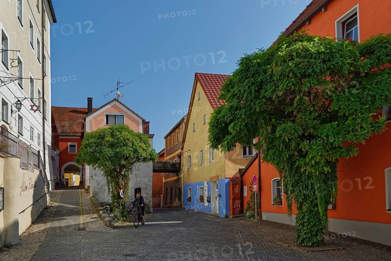 Person riding a bicycle on the Vils alley with historic buildings and cobblestones, Kallmünz, Upper Palatinate, Bavaria, Germany, Europe
