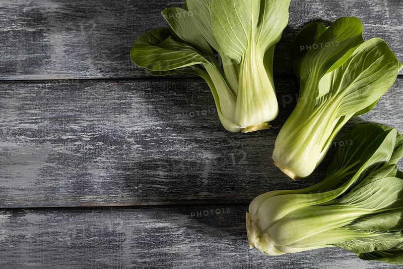 Fresh green bok choy or pac choi chinese cabbage on a gray wooden background. Hard light, contrast. Top view, copy space, flat lay