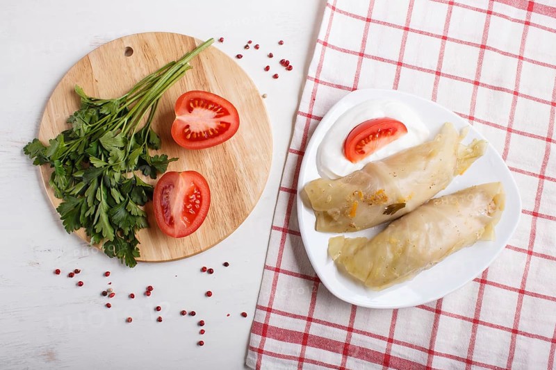 Cabbage rolls with beef, rice and vegetables on a linen tablecloth on a white wooden background. top view, flat lay