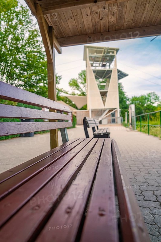A wooden bench next to a hiking trail offers a view of a large modern observation tower, Rappbodetalsperre, Harz, Germany, Europe