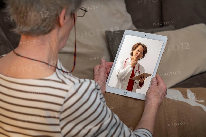 Symbolic image of telemedicine, patient speaking to a doctor in a video conference from home
