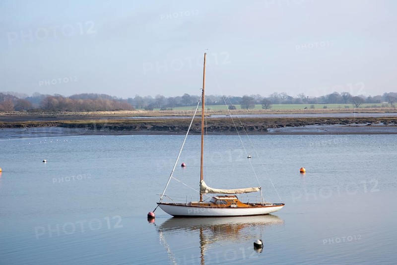 One yacht moored off muddy shore calm water River Deben, Waldringfield, Suffolk, England, UK