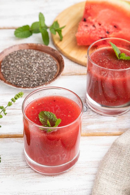 Watermelon juice with chia seeds and mint in glass on a white wooden background with linen textile. Healthy drink concept. Side view, close up