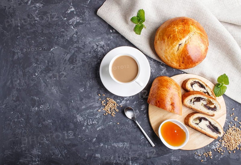 Homemade yeast buns and rolls with poppy seeds and honey on a black concrete background with a cup of coffee. top view, copy space