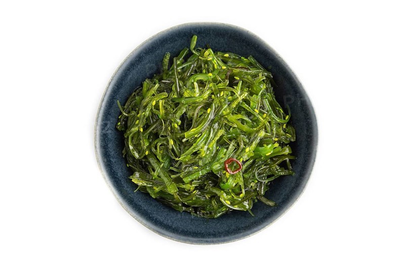 Chuka seaweed salad in blue ceramic bowl isolated on white background. Top view, flat lay