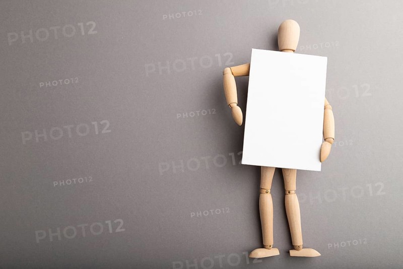 Wooden mannequin holding blank poster on gray pastel background. copy space, isolated, presentation concept