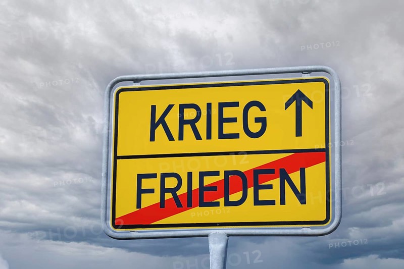 Symbolic image of peace/war: According to a town exit sign, you are leaving peace and travelling towards war (Composing)