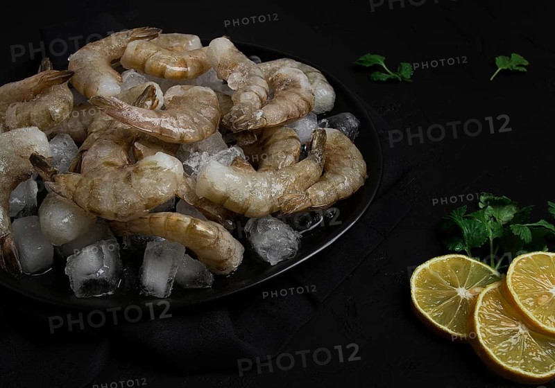 Frozen raw shrimp vannamey, on wooden skewers, ice cubes and lime slices, top view, no people