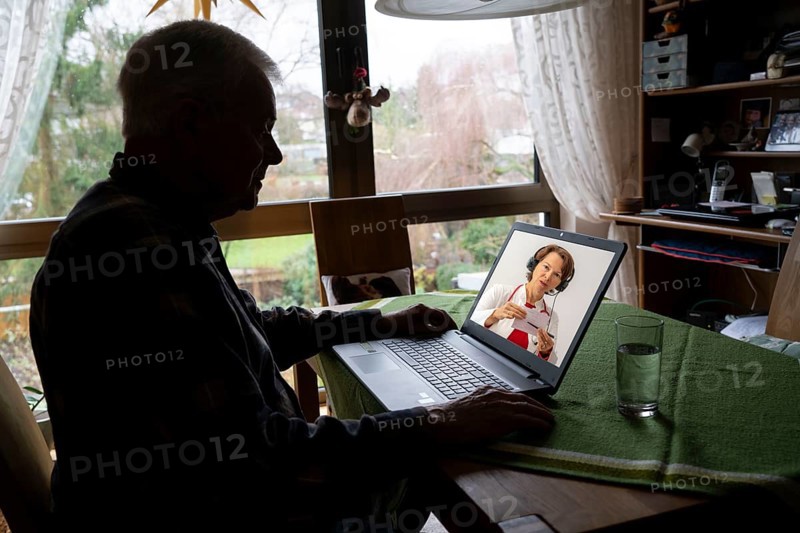 Symbolic image of telemedicine, elderly patient speaking to a doctor in a video conference from home
