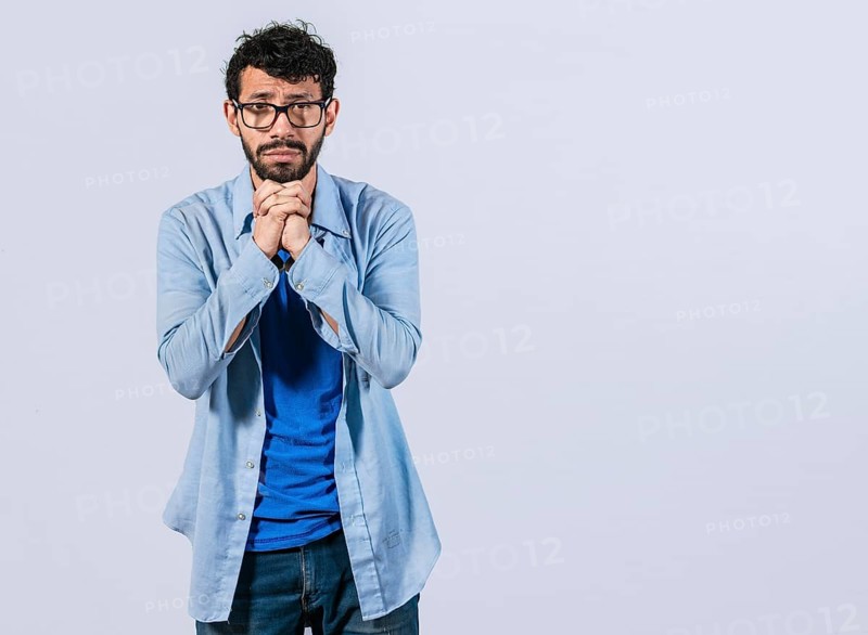 Worried man asking please isolated. Young man putting hands together asking please