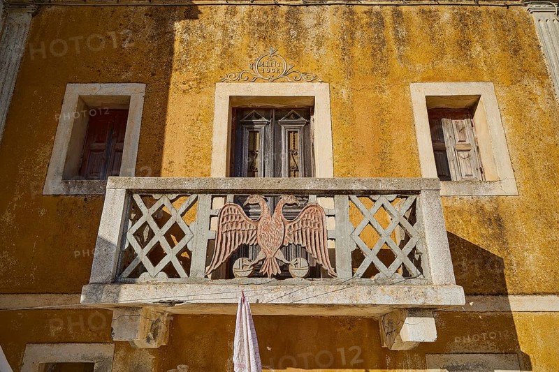 Traditional building with balcony and eagle motif, characterised by yellow colour, Colourful mountain village, Morning light, Olymbos, Karpathos, Dodecanese, Greek Islands, Greece, Europe