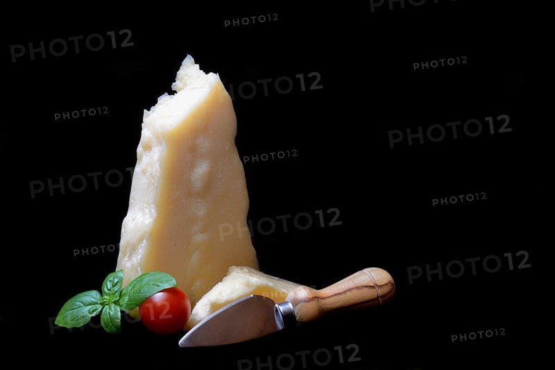 A piece of Parmesan cheese with cheese knife, basil and tomato, Italy, Europe