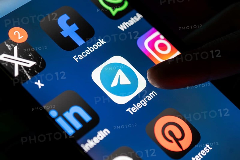 The social media Telegram messenger logo is being displayed on a smartphone screen and on a computer screen