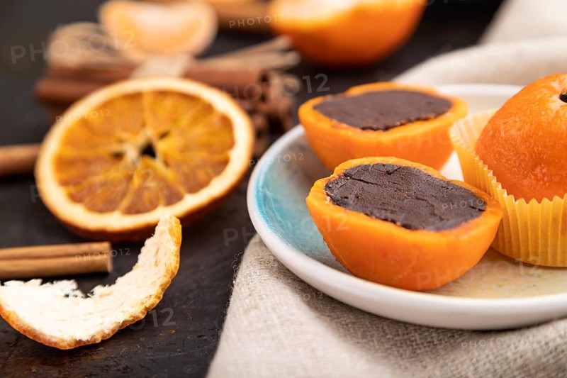 Truffle chocolate tangerine candies on a black concrete background and linen textile. Side view, close up, selective focus