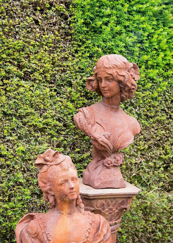 Rusted metal cast iron bust statues female figures, The Walled garden plant nursery, Benhall, Suffolk, England, UK