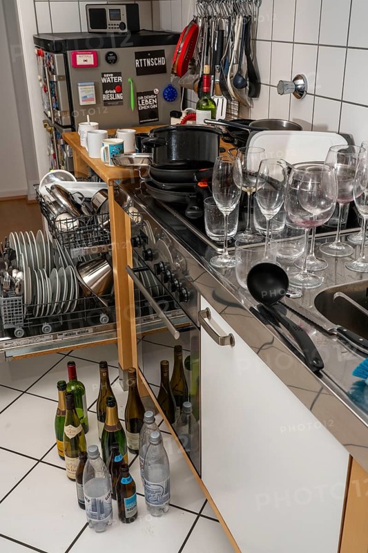 Kitchen after a big dinner, cooking party, dishwasher, full, with cleaned dishes, dirty glasses, pots, cooking utensils on the sink, waiting to be washed