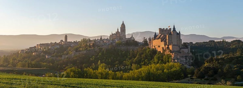 Panoramic view of a historic castle and town surrounded by green fields and mountains at sunrise, Church, Iglesia San Esteban, Cathedral, Alcázar, Alcazar, Segovia, Castilla y León, Leon, Spain, Europe