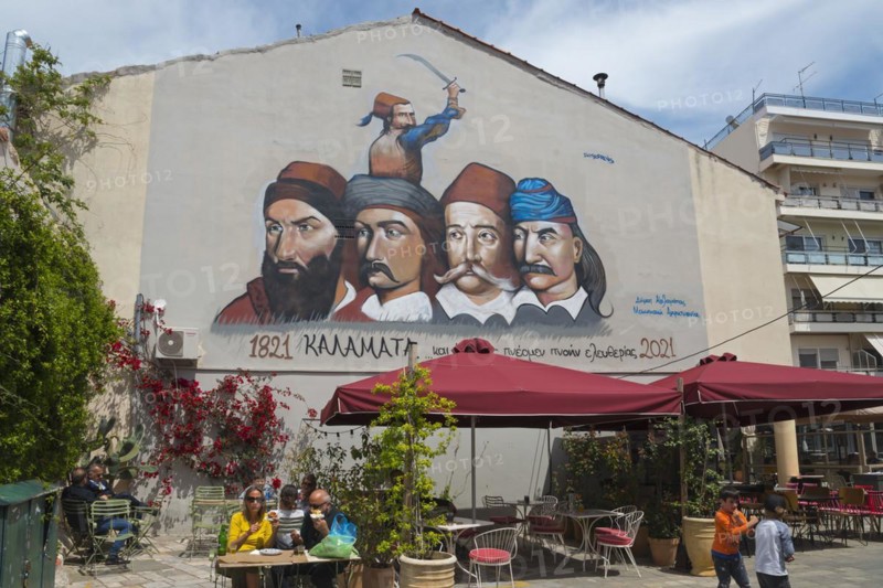 Large mural of historical figures above an urban café with passers-by, graffiti with 5 heroes of the Greek Revolution of 1821 on 23 March Square, Kalamata, Messinia, Peloponnese, Greece, Europe