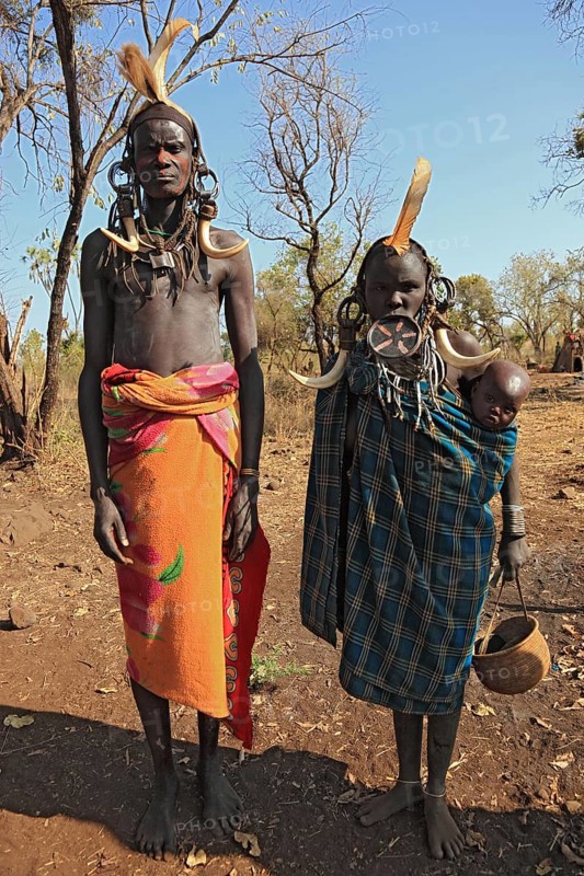 Southern Ethiopia, in Maco National Park, Mursi tribe, Mursi man, Mursi woman with baby, painted skin and headdress, plate-lipped woman, woman with plate in lower lip, Ethiopia, Africa