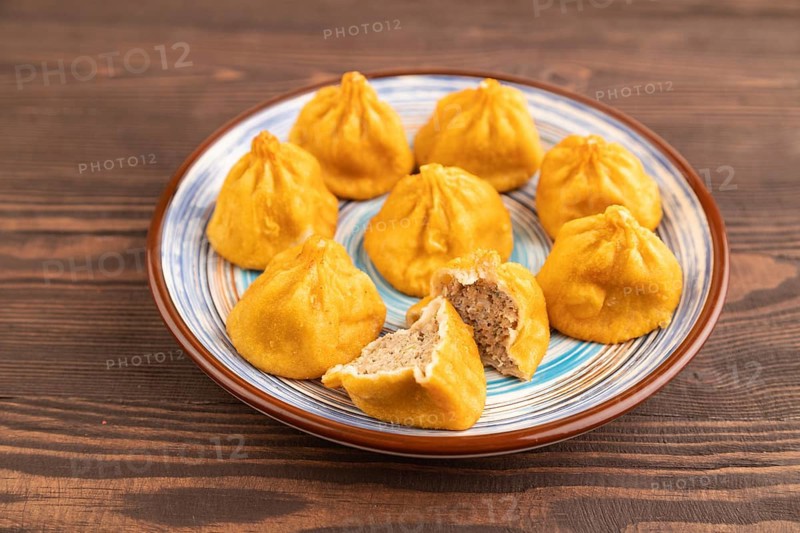 Fried manti dumplings on brown wooden background. Side view, close up