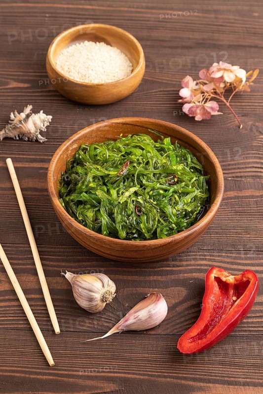 Chuka seaweed salad in wooden bowl on brown wooden background. Side view, close up
